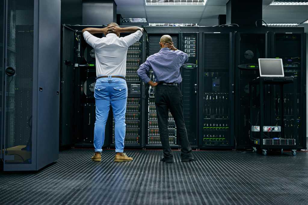 Why do data centers need so much water? Meanwhile in the server room.... Rearview shot of two IT technicians having difficulty repairing a computer in a data center.