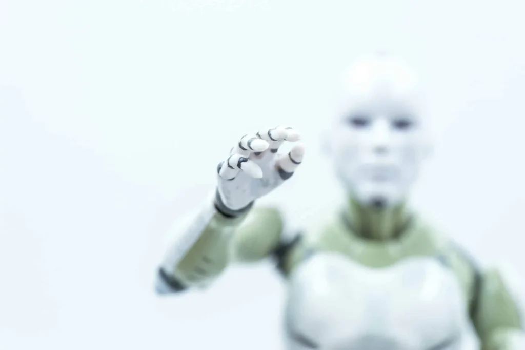 8 Best Robo-Advisors of March 2026 A humanoid robot with an outstretched hand is reaching forward. The image is softly focused, highlighting the robots white and metallic arm and hand against a bright, blurred background.