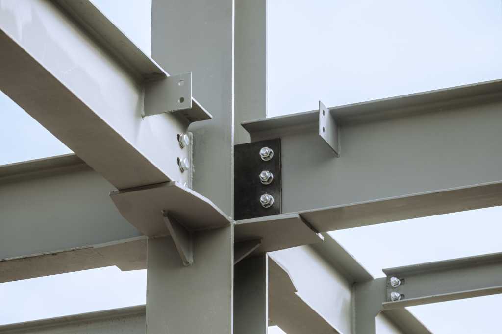 Data centers are moving inland, away from some traditional locations Steel joints. Mounting bolted connection of steel beams before welding. Metal construction covered protective gray primer. Close-up.